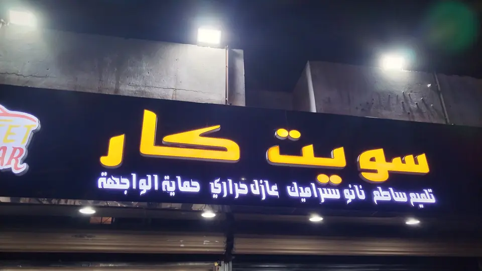 لوحة سويت كار المضيئة بالأصفر على واجهة الورشة ليلًا